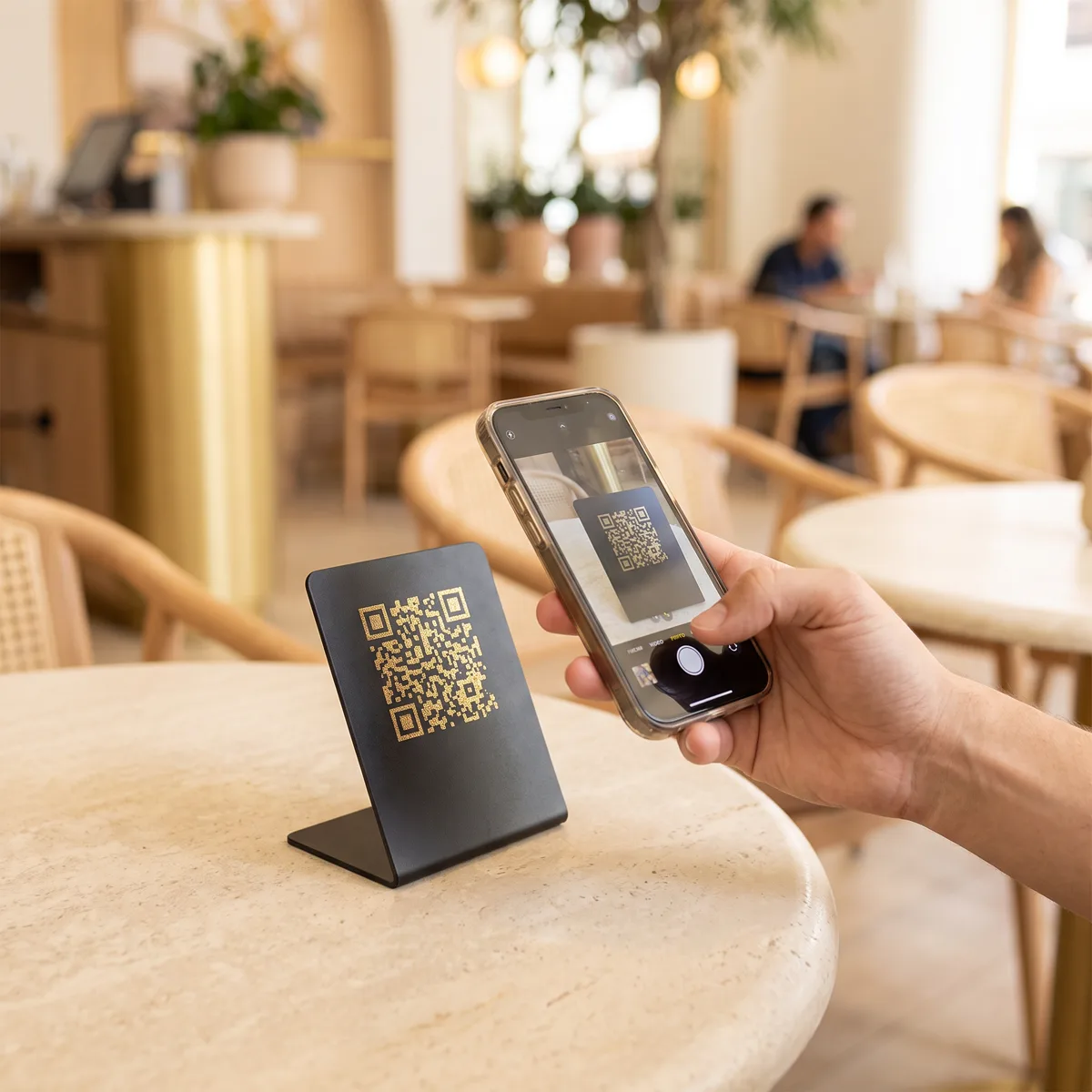 Gast scannt goldenen QR-Code am Restauranttisch mit dem Smartphone
